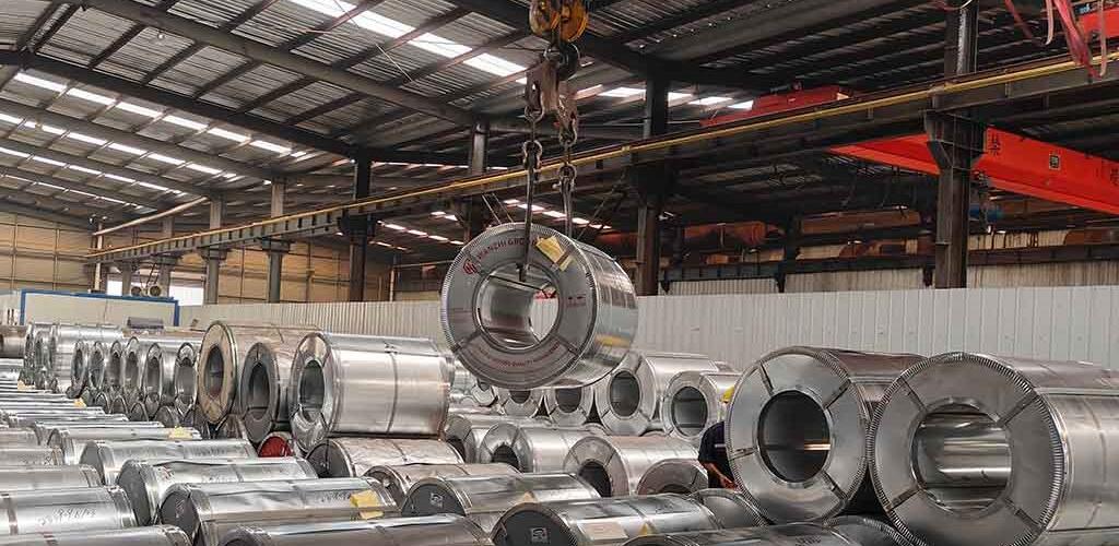 Interior of a stainless steel service center showing coil stock and a rolling line
